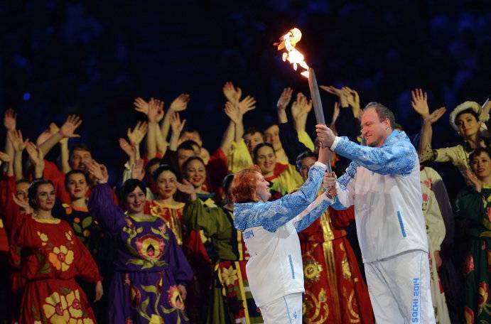 Алексей Ашапатов передает факел паралимпийского огня трехкратной чемпионке Паралимпийских игр по легкой атлетике среди слабовидящих Ольге Семеновой во время церемонии открытия Паралимпиады в Сочи.